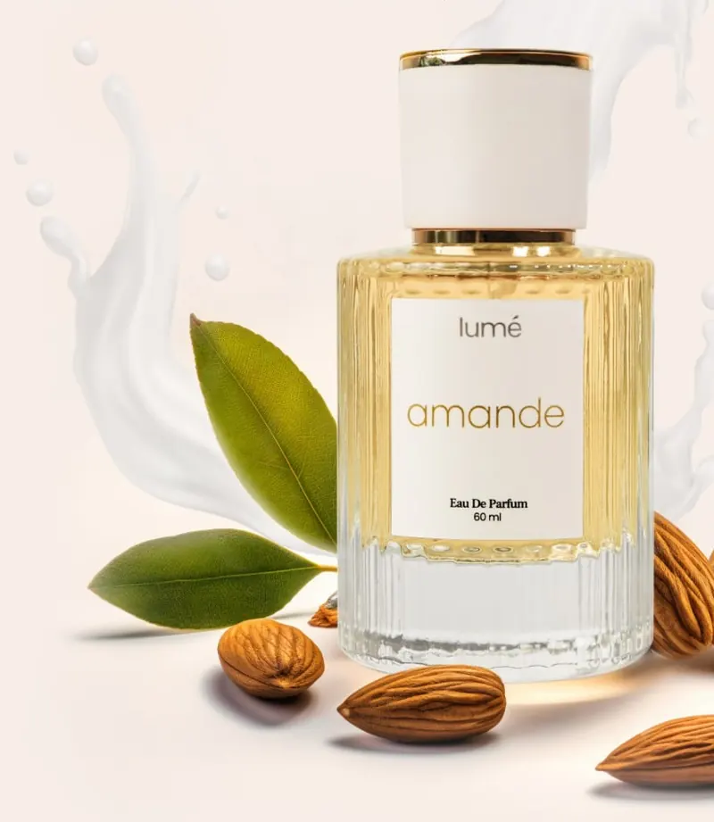 Botol Amande di atas percikan krim, daun dan almond