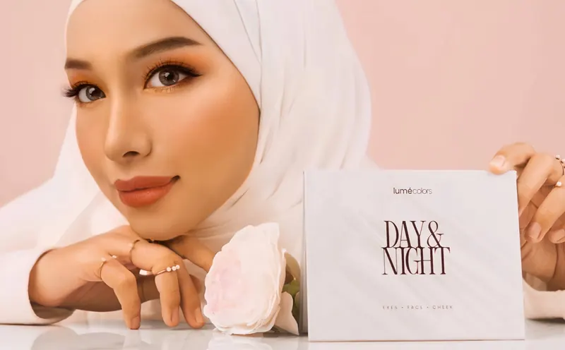 Model berhijab putih bertopang dagu di samping kotak Lumécolors Day & Night dan setangkai mawar