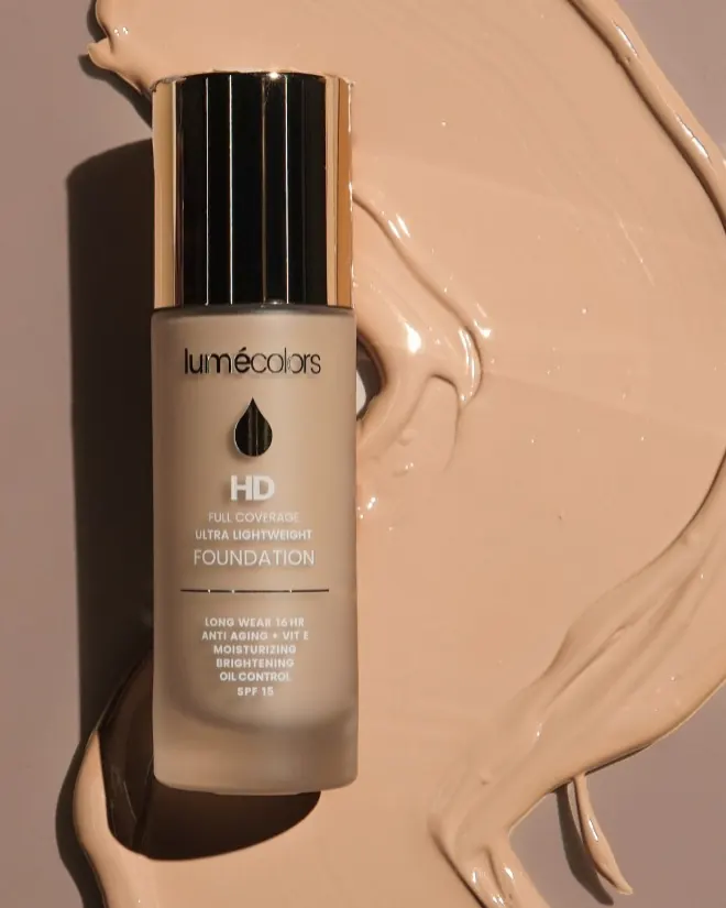 Botol Lumécolors HD Foundation berbaring di atas olesan foundation krem yang mengkilap