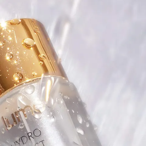Tutup emas dan botol Hydro Boost Essence penuh embun di dalam air