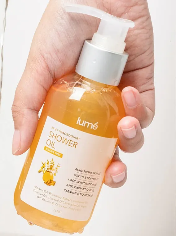 Tangan memegang botol Shower Oil 150 mL di bawah air mengalir
