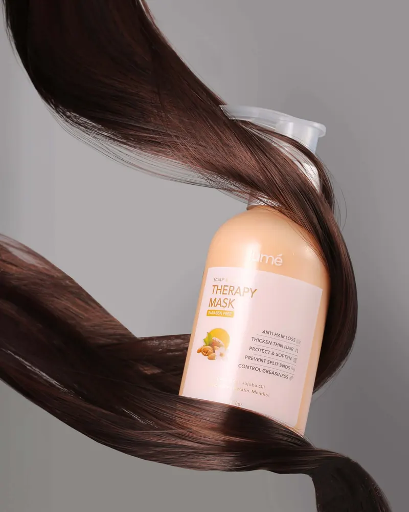 Botol Lume Scalp & Hair Therapy Mask dibalut helaian rambut cokelat yang berkilau