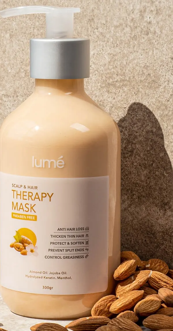 Botol Therapy Mask 300 gr di depan dinding batu dengan kacang almond